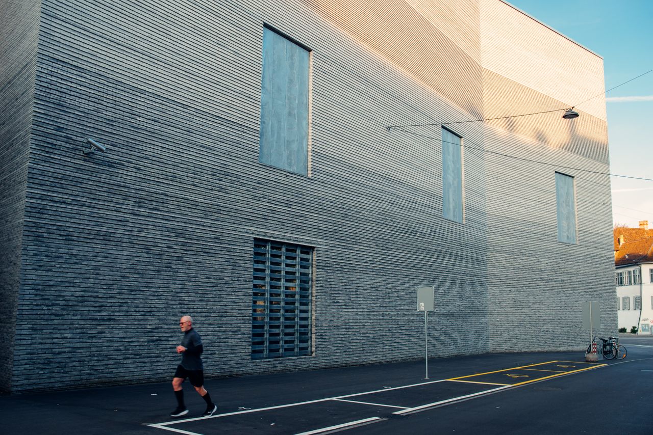 Mastering the First Impression: Your intriguing post title goes here A man jogging past a modern architectural building in Basel, Switzerland.
