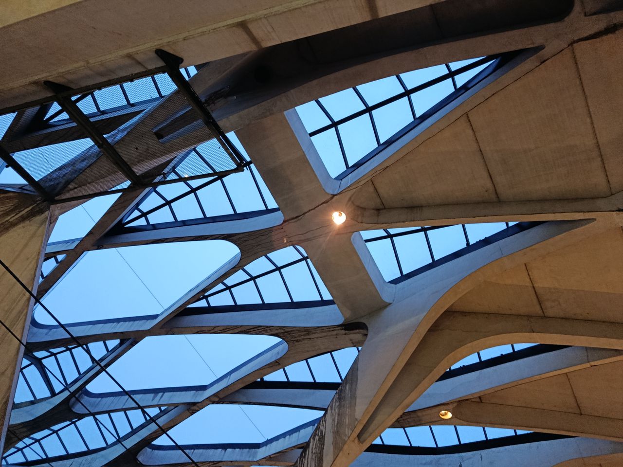 The Art of Drawing Readers In: Your attractive post title goes here Abstract view of a modern ceiling design featuring concrete beams and skylights.