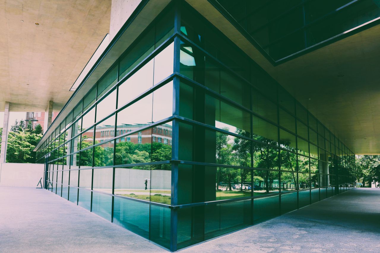 A modern building with a reflective glass facade showcasing greenery in Taiwan.